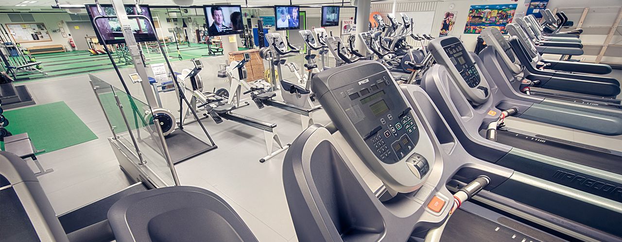 Löpband och crosstrainers på rad framför tv-skärmar i konditionsavdelningen