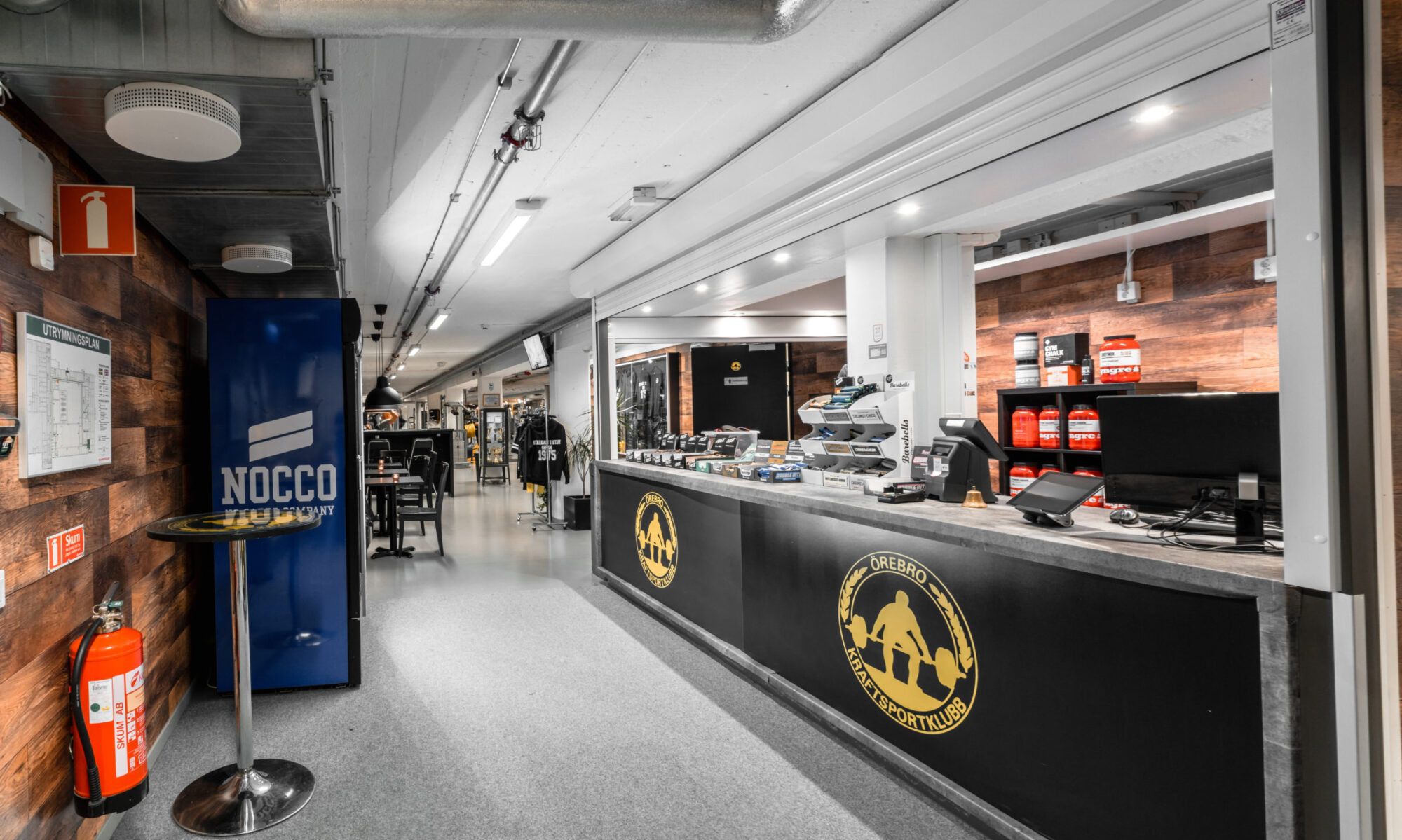 ÖKK:s reception med klubbmärket på disken, café och butik i bakgrunden